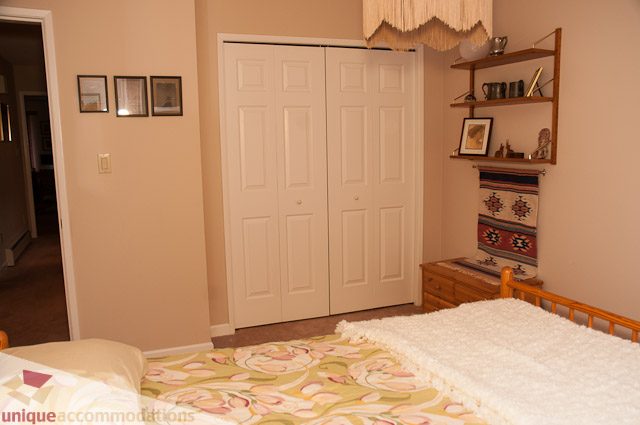 Furnished bedroom with floral bedding and wooden furniture. - 4559 W. 3rd Ave, Vancouver West Side
