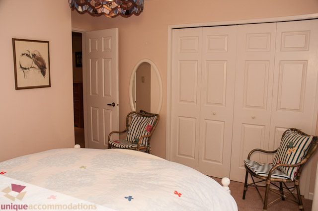 Furnished bedroom with white closet doors and striped chairs. - 4559 W. 3rd Ave, Vancouver West Side