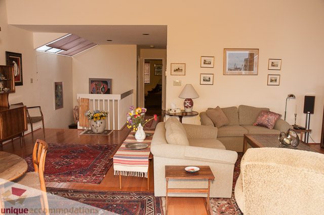 Furnished living room with beige couch, patterned rug, and modern decor. - 4559 W. 3rd Ave, Vancouver West Side