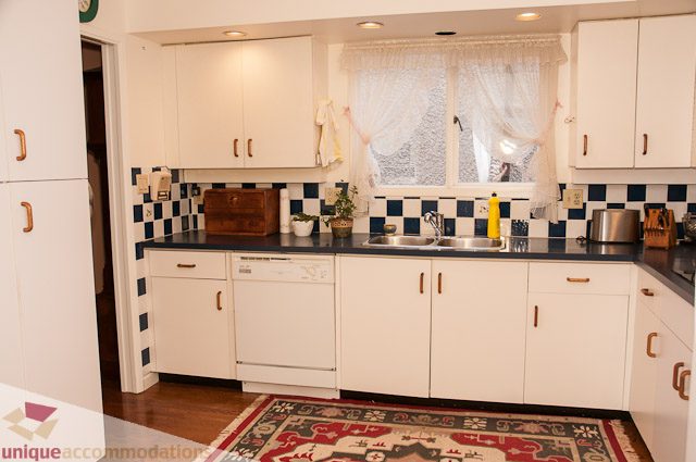 Bright kitchen with white cabinets, checkered backsplash, and hardwood floors. - 4559 W. 3rd Ave, Vancouver West Side