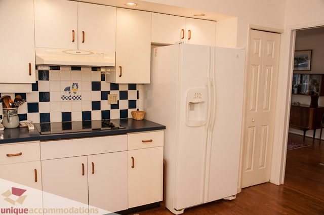 Bright kitchen with white cabinets, black countertops, and checkered backsplash. - 4559 W. 3rd Ave, Vancouver West Side