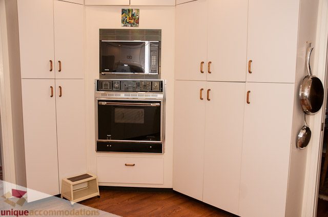 Bright kitchen with white cabinets, stainless steel appliances, and wooden floors. - 4559 W. 3rd Ave, Vancouver West Side