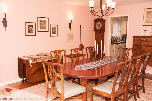 Formal dining room with wooden furniture and a chandelier, leading to a kitchen area. - 4559 W. 3rd Ave, Vancouver West Side