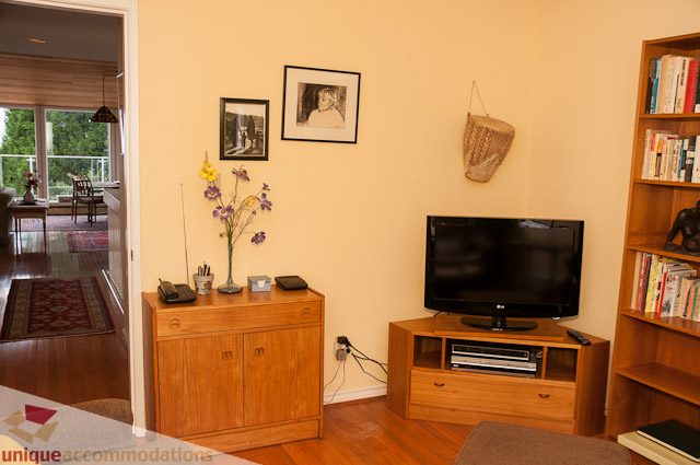 Living room with hardwood floors, bookshelves, and a flat-screen TV. - 4559 W. 3rd Ave, Vancouver West Side