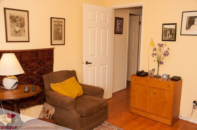 Furnished living room with wooden floors, cozy seating, and framed artwork on the walls. - 4559 W. 3rd Ave, Vancouver West Side