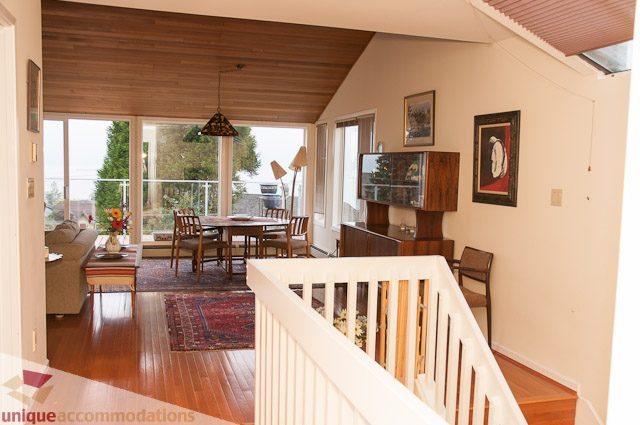 Furnished living room with hardwood floors, large windows, and a view of greenery outside. - 4559 W. 3rd Ave, Vancouver West Side