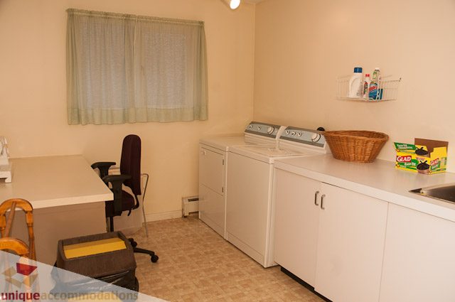 Bright laundry room with white cabinets, countertop, and washing machine. - 4559 W. 3rd Ave, Vancouver West Side