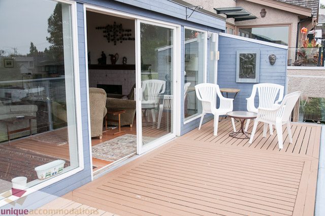 Furnished patio with white plastic chairs and sliding glass doors leading to living room. - 4559 W. 3rd Ave, Vancouver West Side