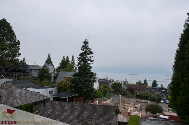 Bright living room with city view and trees in the background. - 4559 W. 3rd Ave, Vancouver West Side
