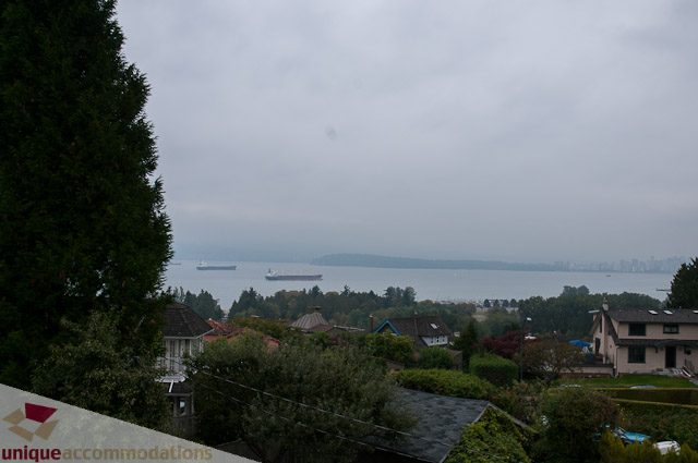 Furnished living room with a stunning city view and lush greenery. - 4559 W. 3rd Ave, Vancouver West Side