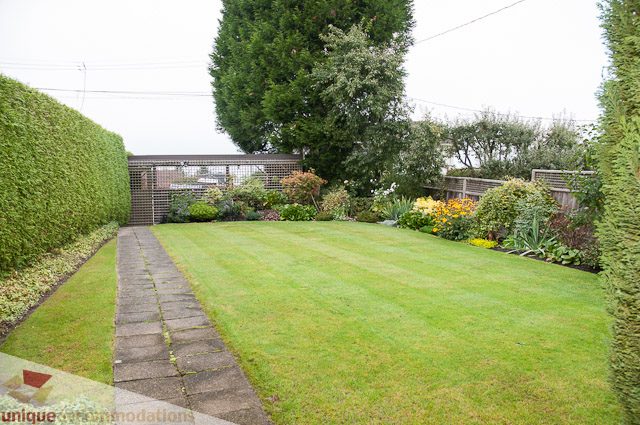 Lush, well-maintained backyard with neatly trimmed grass and vibrant flower beds. - 4559 W. 3rd Ave, Vancouver West Side