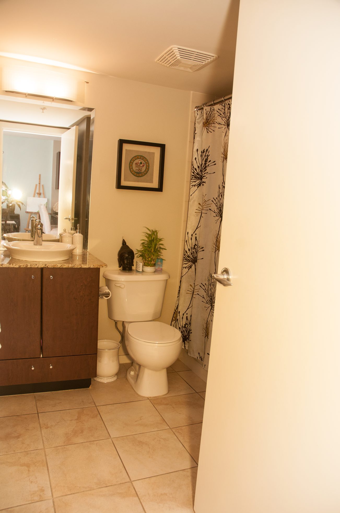Bright bathroom with granite countertops, a potted plant, and a floral shower curtain. - 1405-1155 Seymour Street, Vancouver Downtown