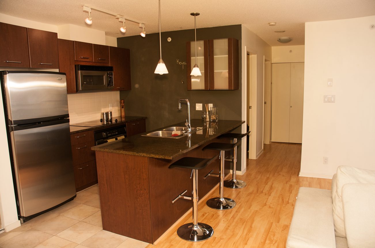 Bright kitchen with dark wood cabinets, granite countertops, and hardwood floors. - 1601-1199 Seymour Street, Vancouver Downtown
