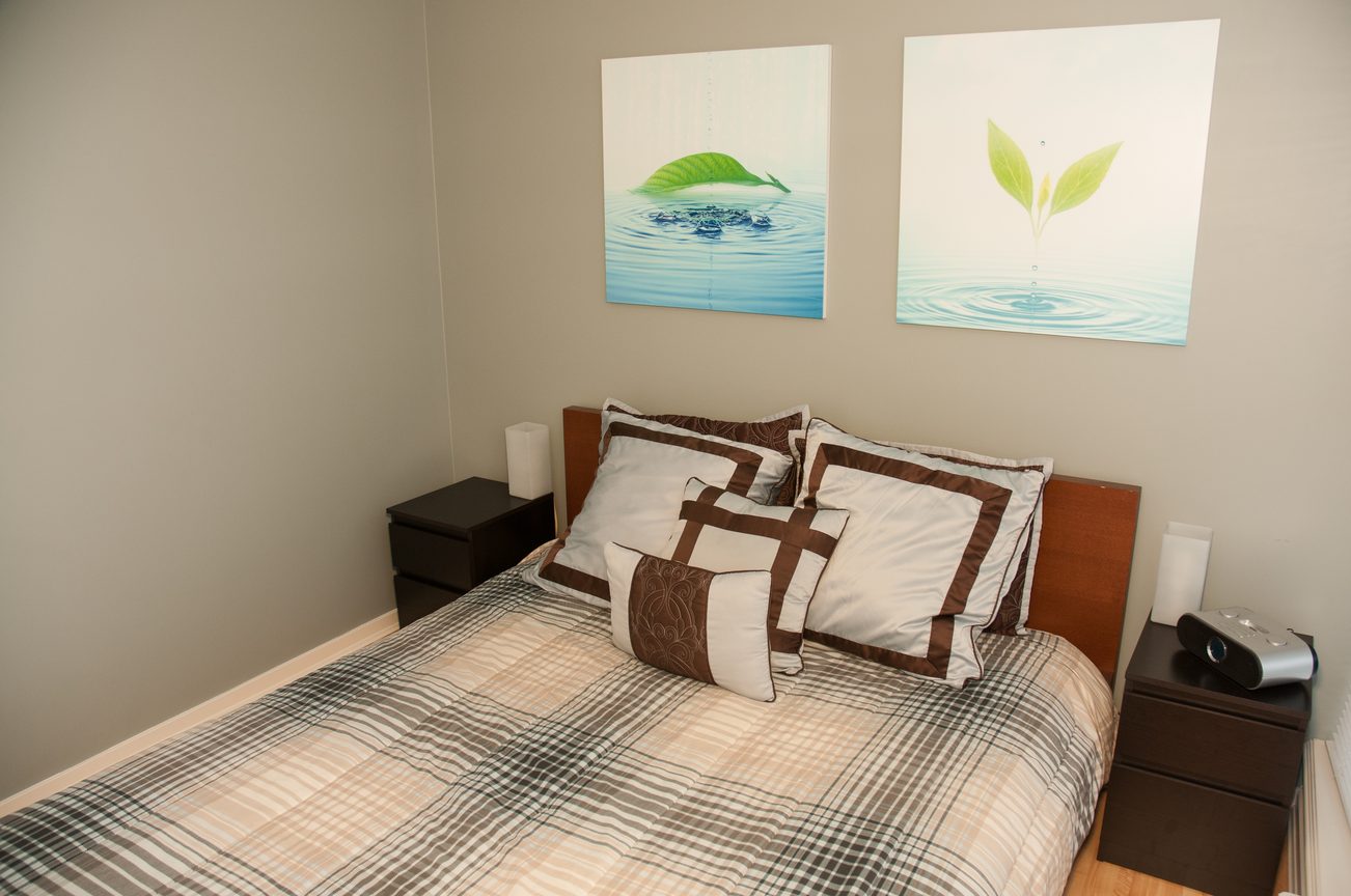 Furnished bedroom with plaid bedding and green leaf artwork above the bed. - 1601-1199 Seymour Street, Vancouver Downtown
