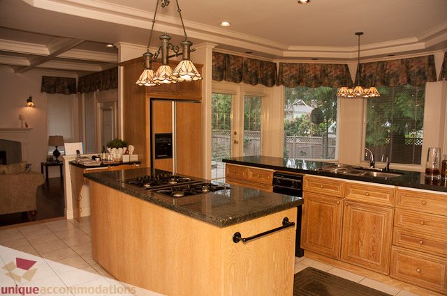 Bright kitchen with wooden cabinets, granite countertops, and a city view. - 1115 Prospect Ave, North Vancouver
