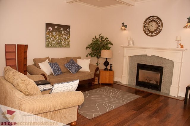 Furnished living room with hardwood floors, fireplace, and large window view. - 1115 Prospect Ave, North Vancouver