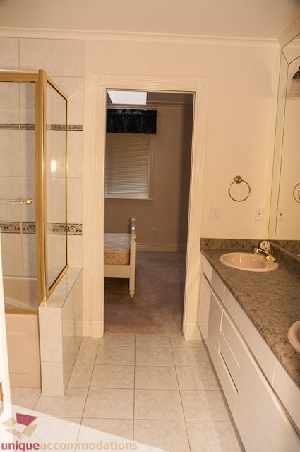 Bathroom with granite countertop and gold fixtures; adjacent bedroom visible. - 1115 Prospect Ave, North Vancouver