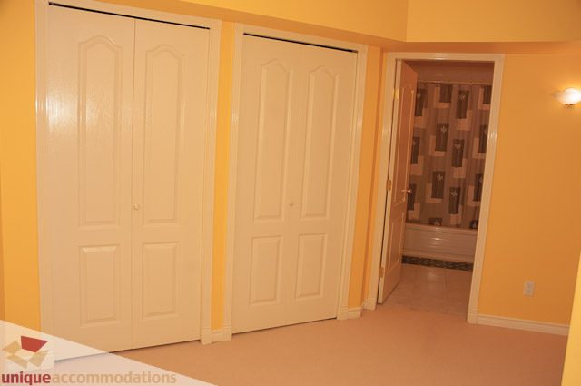 Bright entryway with white closet doors and a partially open door leading to another room. - 1115 Prospect Ave, North Vancouver