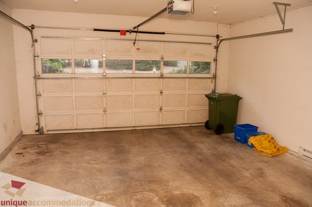 Garage with open door, concrete floor, and trash bin. - 1115 Prospect Ave, North Vancouver
