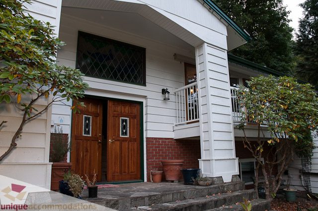 Bright entryway with wooden door and brick accents, leading to a cozy interior. - 1650 Riverside Drive, North Vancouver