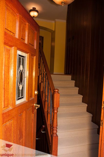 Staircase leading to upper floor with wooden banister and carpeted steps. - 1650 Riverside Drive, North Vancouver