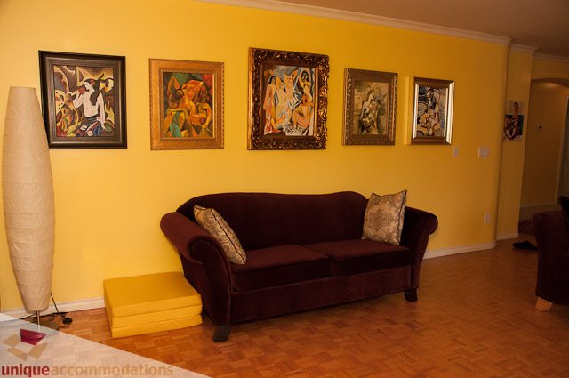 Furnished living room with yellow walls, modern art, and dark furniture. - 1650 Riverside Drive, North Vancouver
