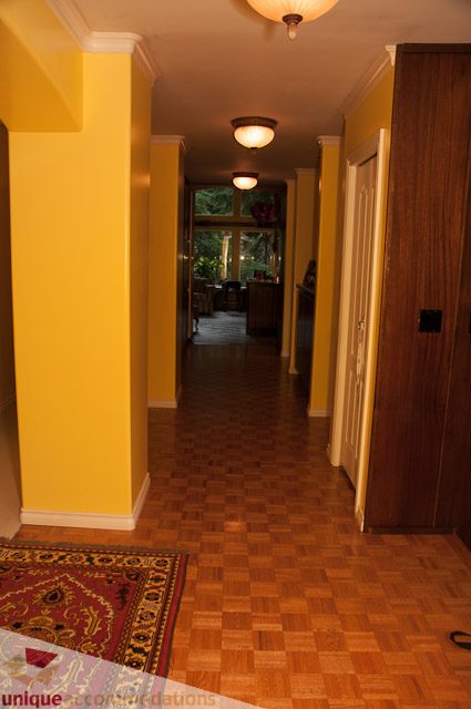 Foyer with wooden floors, yellow walls, and a view to the living area. - 1650 Riverside Drive, North Vancouver