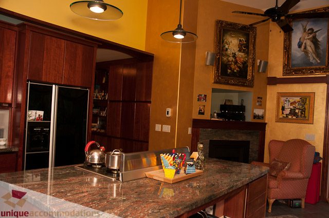 Bright kitchen with granite countertops and wooden cabinets, featuring a stainless steel fridge and a cozy fireplace in...