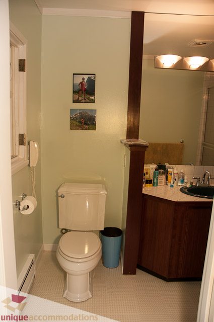 Bathroom with wooden vanity, toiletries, and framed mountain art. - 1650 Riverside Drive, North Vancouver