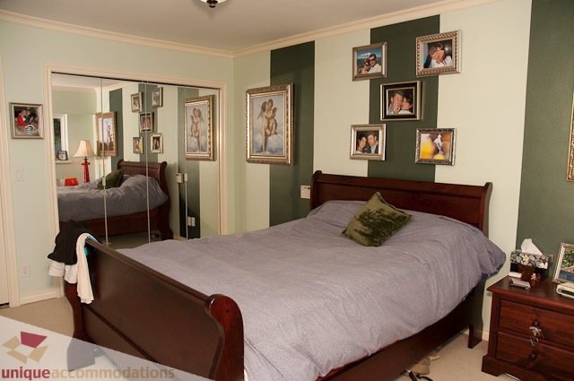 Furnished bedroom with a large bed, framed pictures on the wall, and a mirrored closet. - 1650 Riverside Drive, North Vancouver