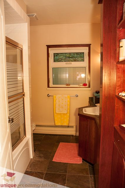 Bathroom with wooden cabinets, tiled floor, and a yellow towel on a towel rack. - 1650 Riverside Drive, North Vancouver