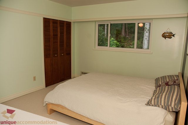 Bright bedroom with wooden closet and window view of trees. - 1650 Riverside Drive, North Vancouver