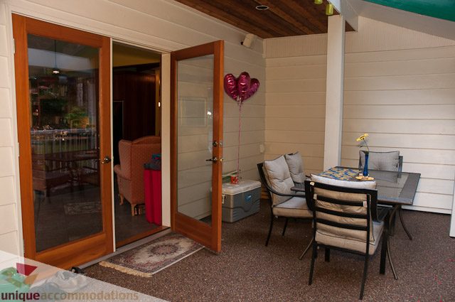 Furnished living room with sliding glass doors, cozy seating, and a small dining area. - 1650 Riverside Drive, North Vancouver