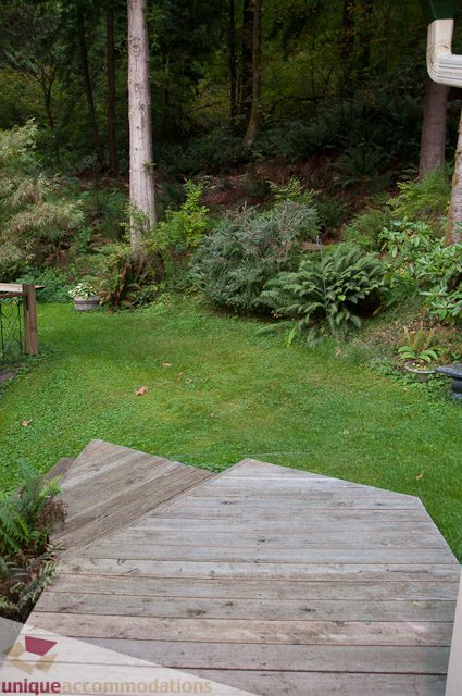 Furnished patio with wooden deck and lush greenery. - 1650 Riverside Drive, North Vancouver
