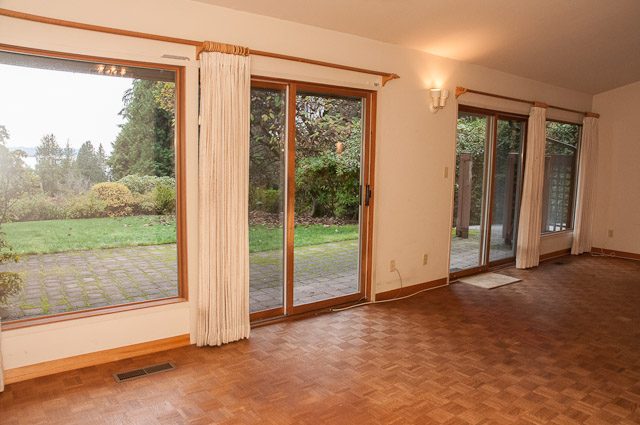 Bright living room with hardwood floors and large sliding glass doors opening to a garden. - 2919 Mathers Ave, West Vancouver