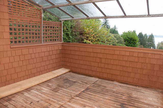 Cozy sunroom with wooden deck and privacy screen, overlooking greenery. - 2919 Mathers Ave, West Vancouver