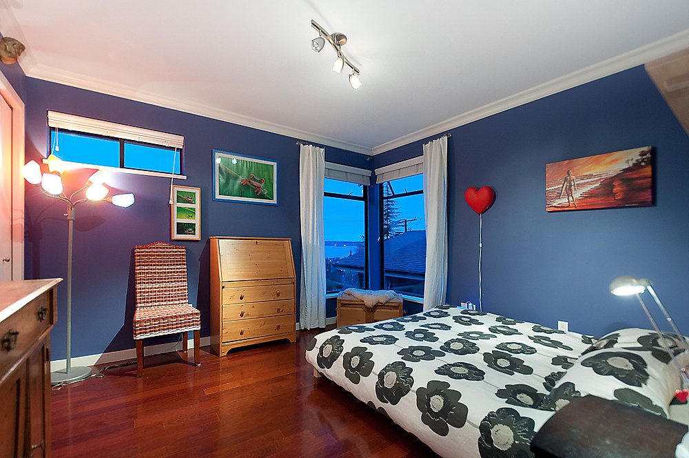 Furnished bedroom with hardwood floors, city view, and colorful decor. - 1119 Keith Road, West Vancouver
