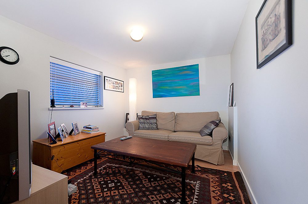 Bright living room with wooden coffee table, patterned rug, and abstract art on the wall. - 1119 Keith Road, West Vancouver