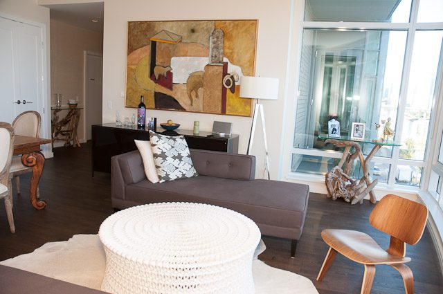 Bright living room with hardwood floors, modern decor, and a city view through large windows. - 501-150 Athletes Way, Vancouver West Side