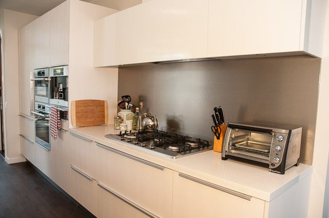 Bright kitchen with white cabinets, stainless steel appliances, and wooden cutting board. - 501-150 Athletes Way, Vancouver West Side