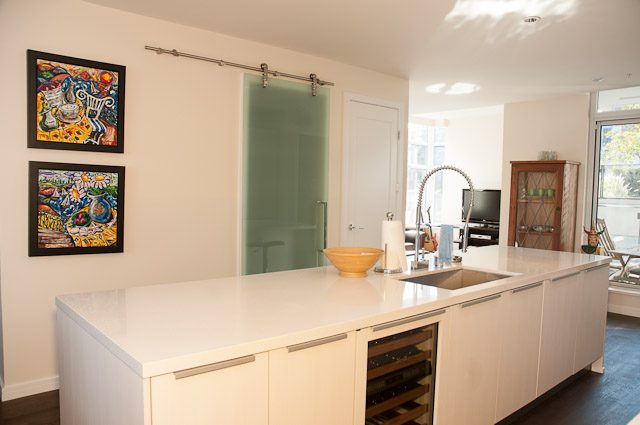 Bright kitchen with white cabinets, granite countertops, and a sliding glass door leading to an outdoor area.