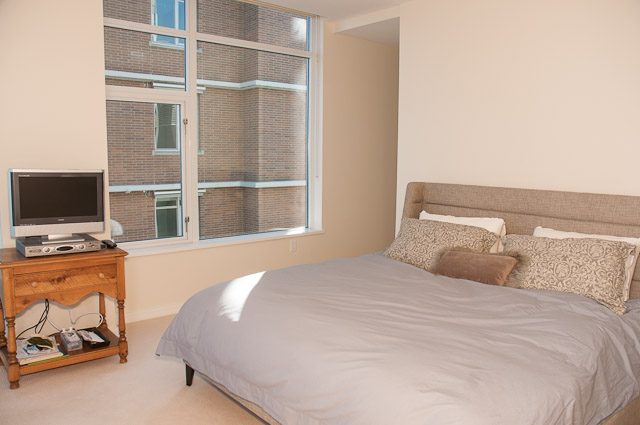 Bright bedroom with large window, city view, and neatly made beds. - 501-150 Athletes Way, Vancouver West Side