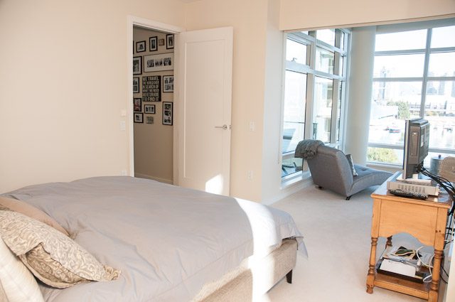 Spacious bedroom with large windows, city view, and cozy furnishings. - 501-150 Athletes Way, Vancouver West Side