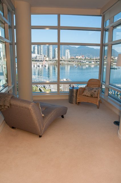 Bright living room with city view and waterfront, furnished with a sofa and armchair. - 501-150 Athletes Way, Vancouver West Side