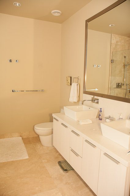 Spacious bathroom with white vanity, beige walls, and large mirror. - 501-150 Athletes Way, Vancouver West Side