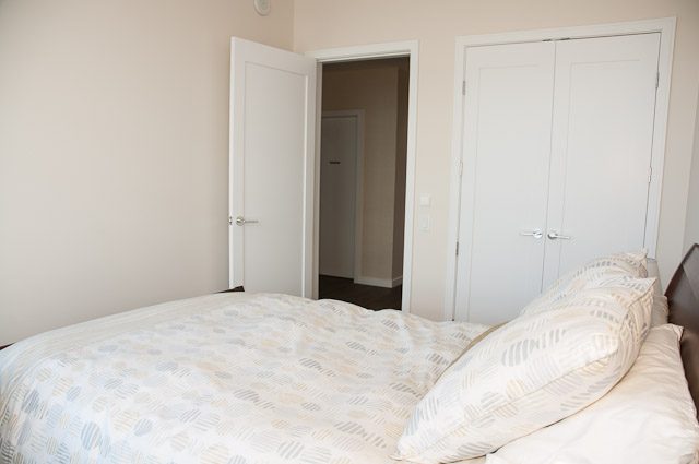 Bright bedroom with neatly made bed and mirrored closet doors. - 501-150 Athletes Way, Vancouver West Side
