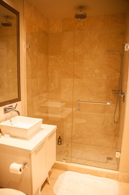 Furnished bathroom with modern sink, glass shower, and beige tiles. - 501-150 Athletes Way, Vancouver West Side
