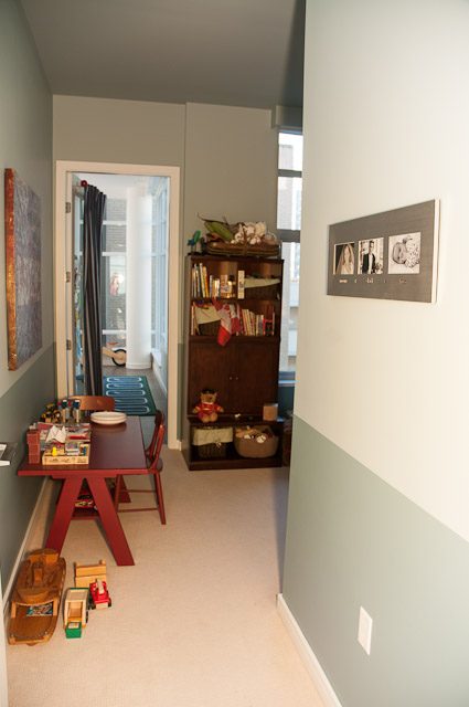 Bright living room with wooden furniture, toys, and a bookshelf. - 501-150 Athletes Way, Vancouver West Side