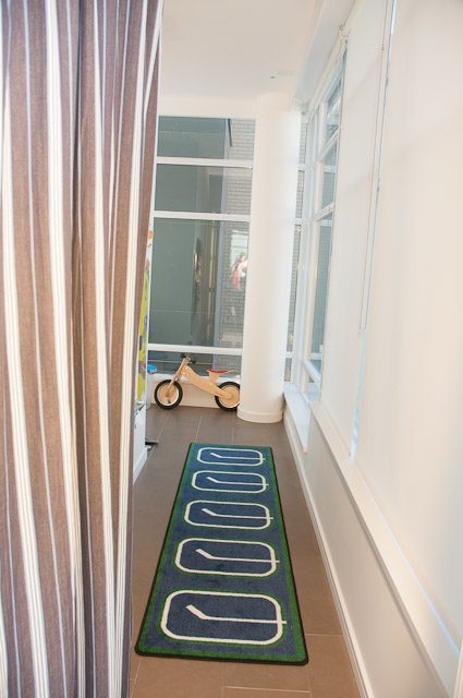 Bright hallway leading to living area with hardwood floors and a colorful rug. - 501-150 Athletes Way, Vancouver West Side