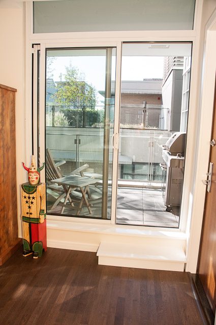 Bright living room with hardwood floors, sliding glass doors leading to a patio, and a quirky clown figurine.